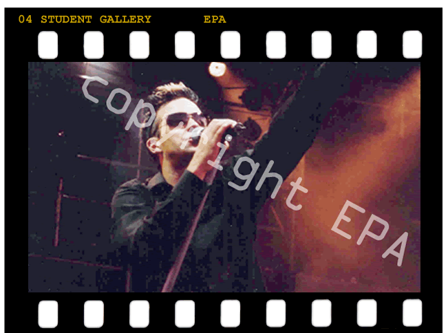 Rock star Robbie Williams performing on stage holding microphone stand